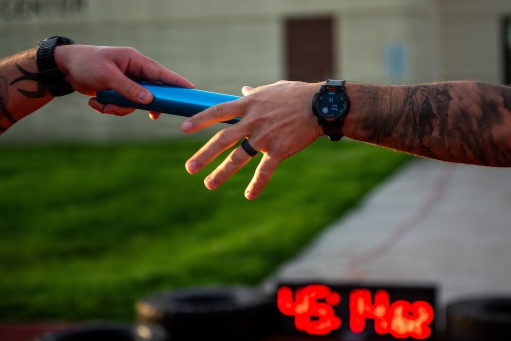 Close up of Airmen's hands exchanging a baton