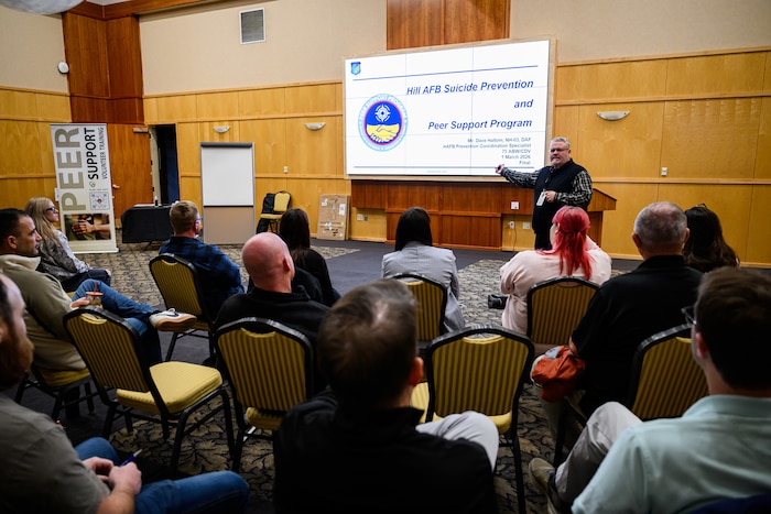 Dave Haltom stands in front of a group of peer support volunteers instructing them.