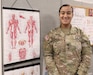 U.S. Army Reserve Spc. Angelica Parrilla, assigned to Surgeons office from the 1st Mission Support Command, poses next to her office cubicle diagram of the human body. (U.S. Army Reserve photo by Spc. Eric Javier II Amaro-Millan).