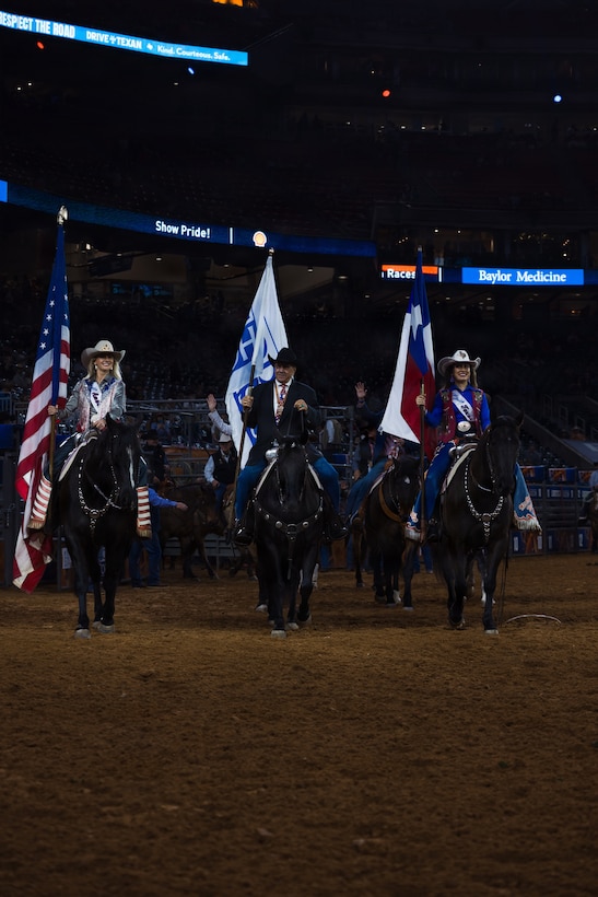 Houston Livestock Show and Rodeo staff ride into the main rodeo arena during the Grand Entry on Armed Forces Appreciation Day in Houston, March 4, 2026. Armed Forces Appreciation Day honored nearly 4,000 military personnel and veterans, including a joint service enlistment ceremony for approximately 500 recruits. (U.S. Marine Corps photo by SSgt. Ethan M. LeBlanc)