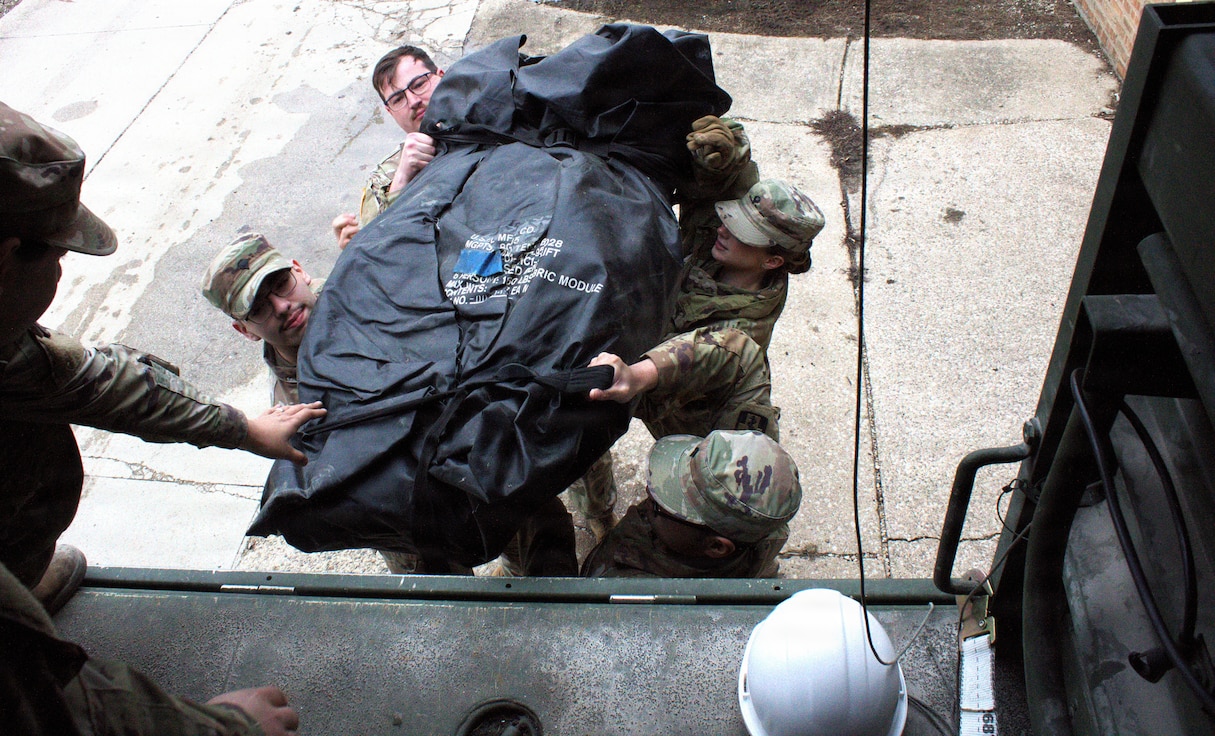 Soldiers of the 708th Medical Company Ground Ambulance load supplies into the back of a light medium tactical vehicle in preparation for shuttle operations.