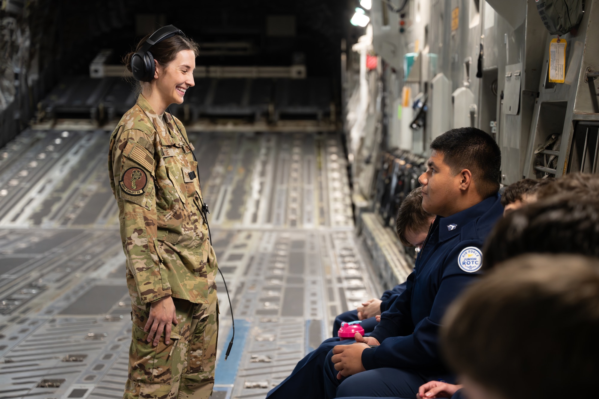 U.S. Air Force Staff Sgt. Jolan Besse, 58th Airlift Squadron instructor loadmaster, speaks with a Junior Reserve Officers' Training Corps cadet from Detachment OK-20061 during a C-17 Globemaster III incentive flight at Altus Air Force Base, Oklahoma, March 3, 2026. C-17 loadmasters calculate and verify cargo weight and balance to help keep the aircraft within safe operating limits. (U.S. Air Force photo by Airman 1st Class Nathan Langston)