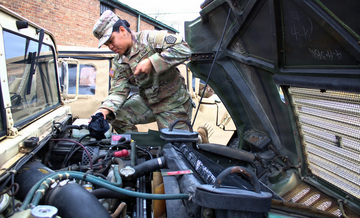 Spc. Angie Cartagena, a Soldier with the 108th Multifunctional Medical Battalion, performs preventive maintenance checks and services on a High Mobility Multipurpose Wheeled Vehicle prior to using it as part of the Forest Park St. Patrick's Day parade.