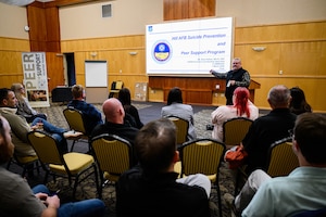 Dave Haltom stands in front of a group of peer support volunteers instructing them.