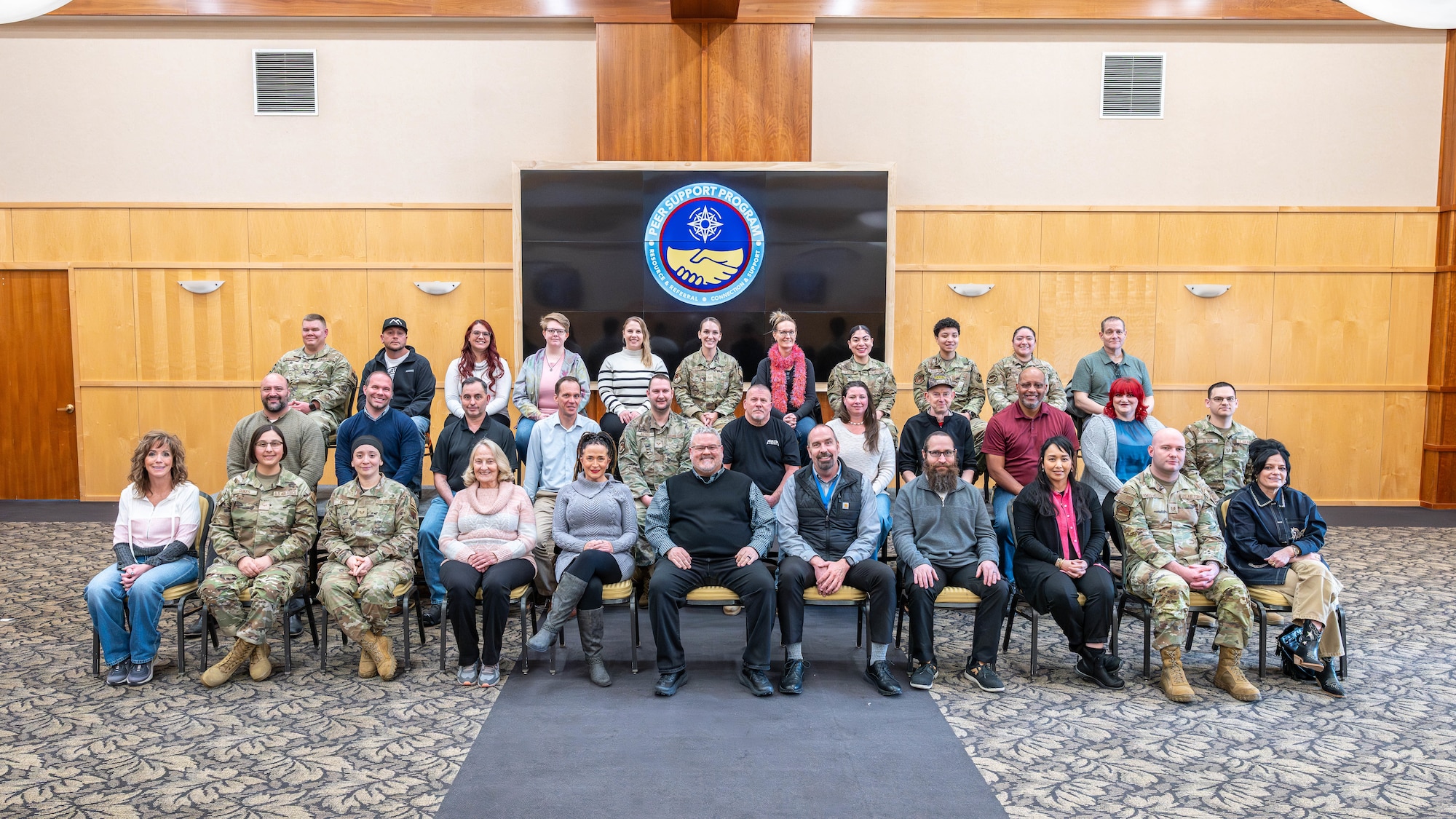 Three rows of peer support volunteers pose for a group photo.