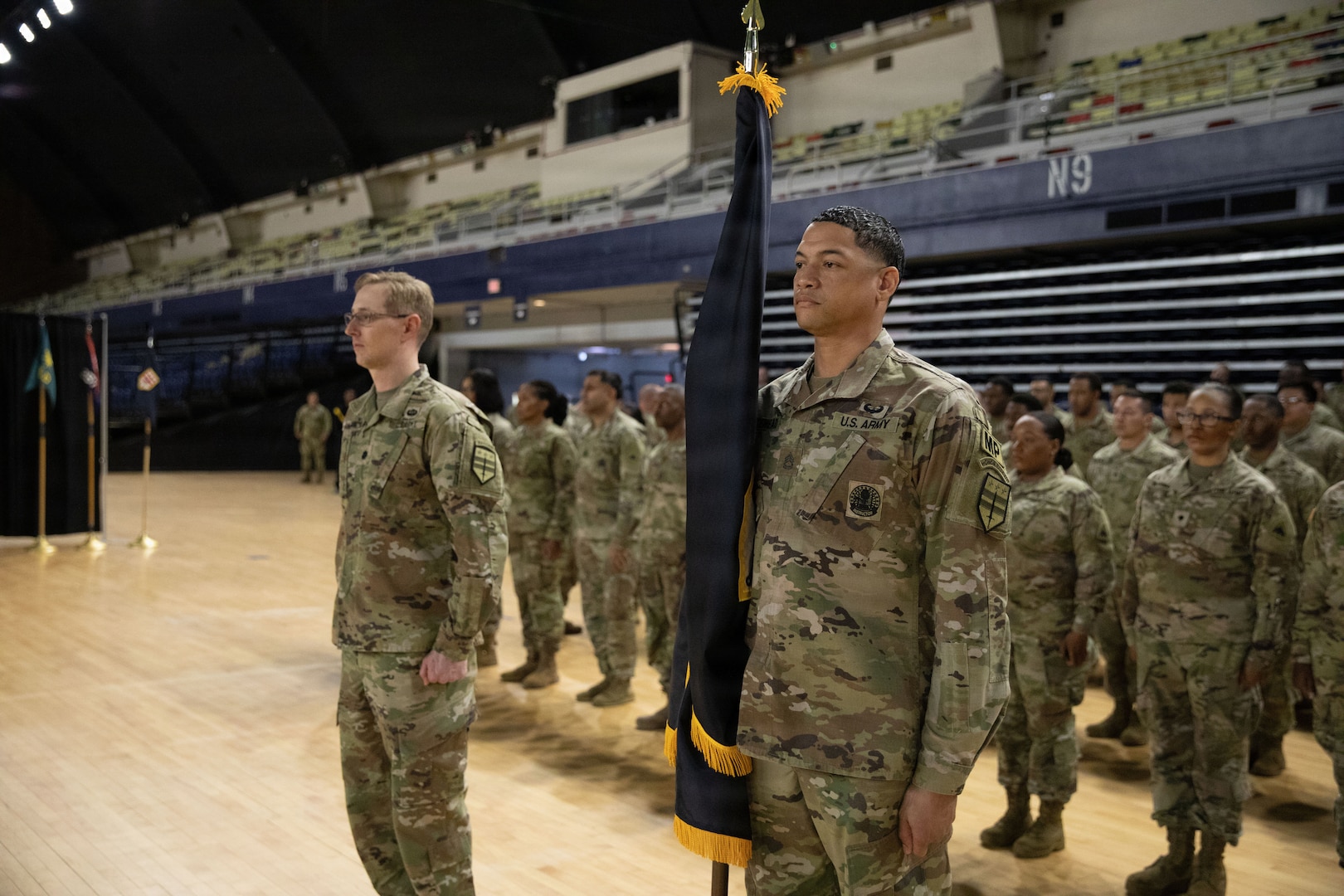 U.S. Army Sgt. 1st Class Kevin Whitehead (left) and Lt. Col. Andrew Garwitz (right), both with the D.C. National Guard, stand in front of the formation with the brigade colors during the 260th Special Purpose Brigade activation ceremony at the activation ceremony at the D.C. Armory in Washington, D.C., March 7, 2026.