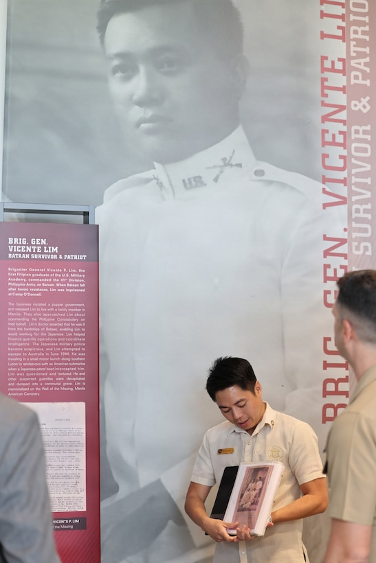 Vicente Lim IV, Manila American Cemetery and Memorial staff member, stands in front of a banner depicting his great grandfather, Vicente Lim, a key figure in Filipino history, March 6, 2026.