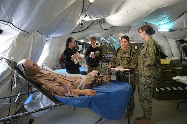 Expeditionary Medical Facility Kilo medical staff review and discuss a treatment plan for a simulated patient during an EMF training at Naval Expeditionary Medicine Warfighter Development Center, Camp Pendleton, California, Feb. 9–18, 2026. The training emphasizes teamwork, communication, and clinical decision-making in a fast-paced expeditionary medical setting. (U.S. Navy photo by Petty Officer 2nd Class Leandra Mojica)
