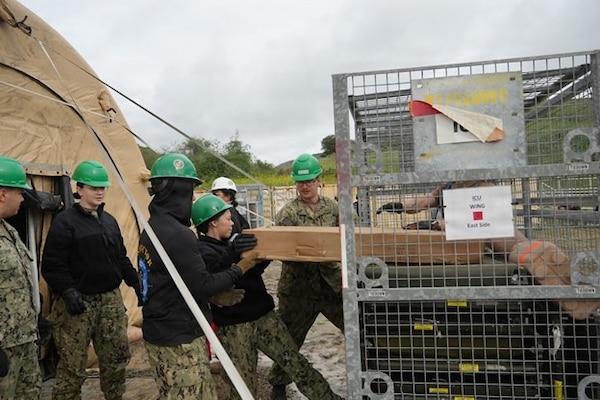 Sailors assigned to Expeditionary Medical Facility (EMF) Kilo, Camp Lejeune, North Carolina, remove consumables from shark cages to prepare their functional area during an EMF training at the Naval Expeditionary Medicine Warfighter Development Center, Camp Pendleton, California, Feb. 9–18, 2026. The evolution trains Sailors to organize and stage supplies for rapid access during patient care operations. (U.S. Navy photo by Petty Officer 2nd Class Leandra Mojica)