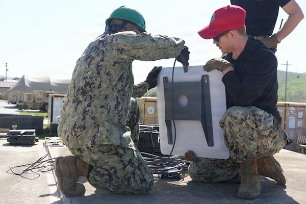 Naval Expeditionary Medicine Warfighter Development Center (NEMWDC) Information Systems Technician 2nd Class Ryan Eldard, instructs Electronics Technician 3rd Class Rafi Galib, electronics technician assigned to Expeditionary Medical Facility (EMF) Kilo, Camp Lejeune, North Carolina, on setting up the sound system during an EMF training at NEMWDC, Camp Pendleton, California, Feb. 9–18, 2026. The communications setup supports command and control and ensures information can be rapidly disseminated throughout the EMF during simulated operations. (U.S. Navy photo by Petty Officer 2nd Class Leandra Mojica)