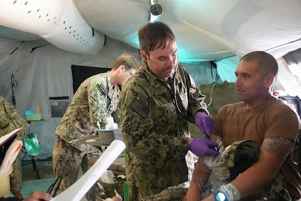 Ensign Zachary Howell, medical surgical nurse assigned to Expeditionary Medical Facility Kilo, Camp Lejeune, North Carolina, checks the vitals of a simulated patient during EMF training at the Naval Expeditionary Medicine Warfighter Development Center, Camp Pendleton, California, Feb. 9–18, 2026. The scenario trains medical staff to conduct rapid patient assessments and prioritize care in an austere, deployed environment. (U.S. Navy photo by Petty Officer 2nd Class Leandra Mojica)