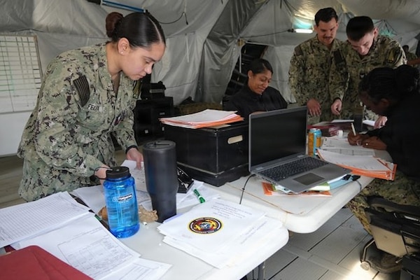 Hospital Corpsman 3rd Class Laura Felix, general duty Corpsman assigned to Expeditionary Medical Facility (EMF) Kilo, Camp Lejeune, North Carolina, reviews paperwork and verifies patient information during EMF training at the Naval Expeditionary Medicine Warfighter Development Center, Camp Pendleton, California, Feb. 9–18, 2026. Accurate documentation supports continuity of care and operational tracking in an expeditionary medical environment. (U.S. Navy photo by Petty Officer 2nd Class Leandra Mojica)