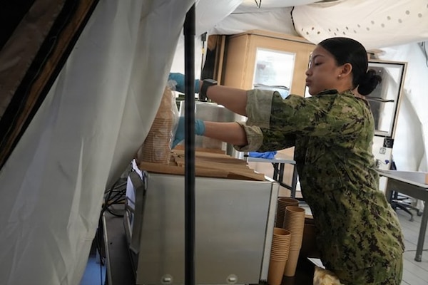 Culinary Specialist 3rd Class Marjorie Gabrino, culinary specialist assigned to Expeditionary Medical Facility (EMF) Kilo, Camp Lejeune, North Carolina, prepares for lunch in the EMF galley during training at Naval Expeditionary Medicine Warfighter Development Center, Camp Pendleton, California, Feb. 9–18, 2026. Meal preparation is part of sustainment operations that keep medical teams fueled and focused during field exercises. (U.S. Navy photo by Petty Officer 2nd Class Leandra Mojica)