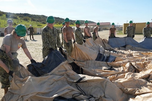 Sailors with Expeditionary Medical Facility (EMF) Kilo spread out an air beam tent before inflating it during an EMF training at Camp Pendleton, California, Feb. 9–18, 2026. The training, held by the Naval Expeditionary Medicine Warfighter Development Center (NEMWDC), prepares Sailors to rapidly establish expeditionary medical infrastructure in support of deployed operations. (U.S. Navy photo by Petty Officer 2nd Class Leandra Mojica)