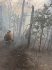 Oklahoma National Guard wildland firefighters partrol a fireline searching for hotspots during fire fighting operations near Talihinia, Oklahoma, Feb. 27, 2026.