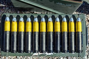 Eleven large munition rounds are lined up on a case outside.