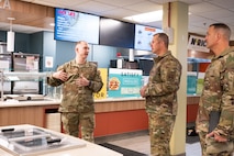 Tech. Sgt. Montana McCormick (left) speaks to Eight Air Force leadership inside a dining facility.