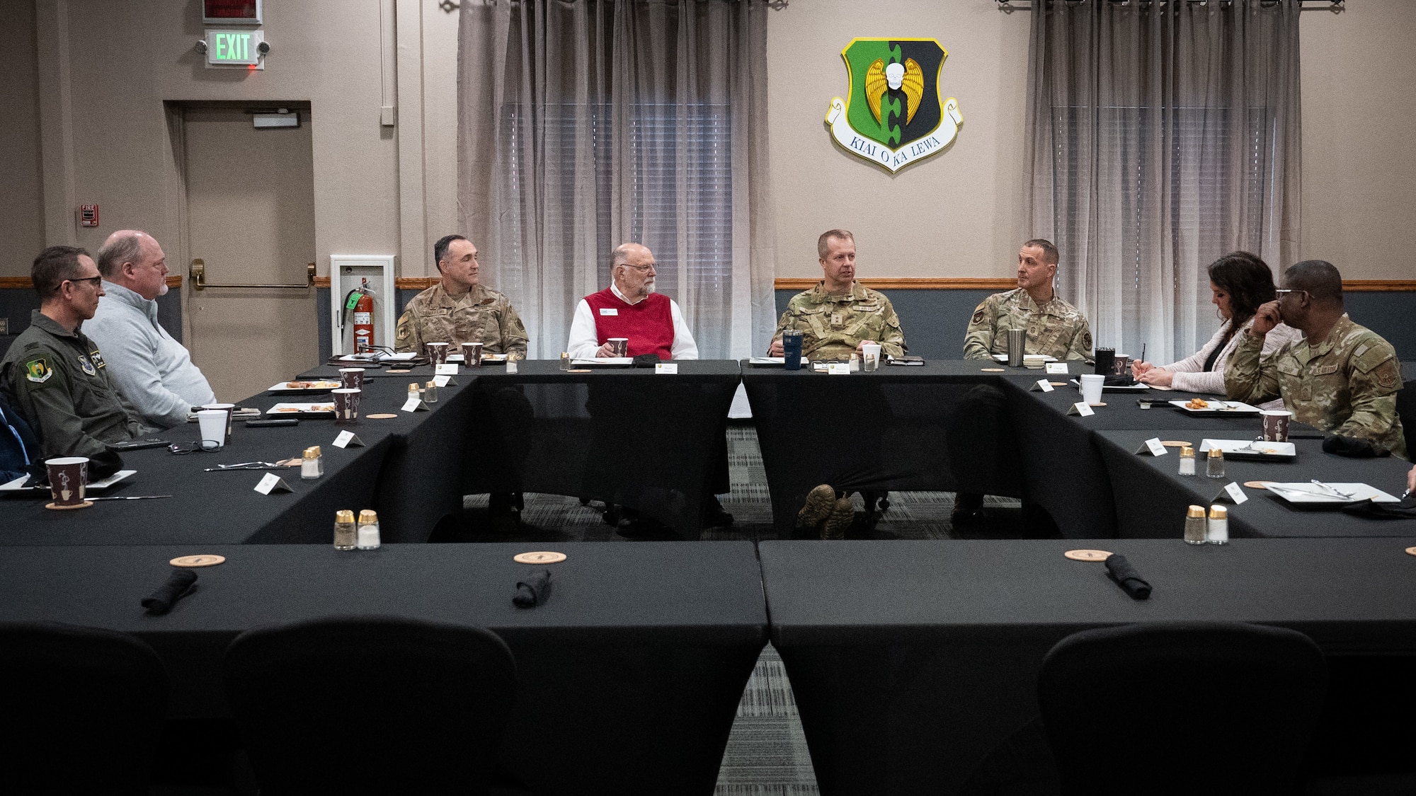 Airmen and civic leaders sit together at a table.