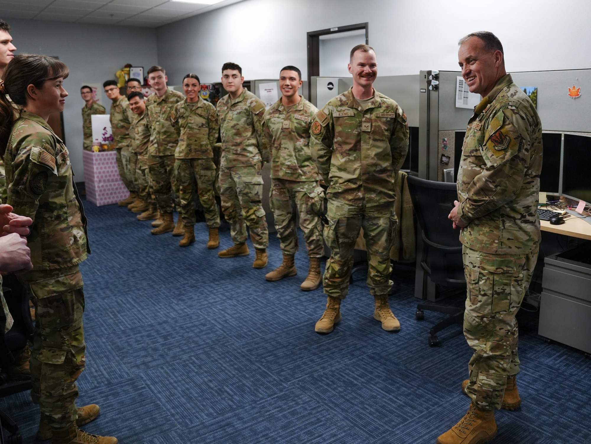 A group of people in military uniforms stand in a room smiling.