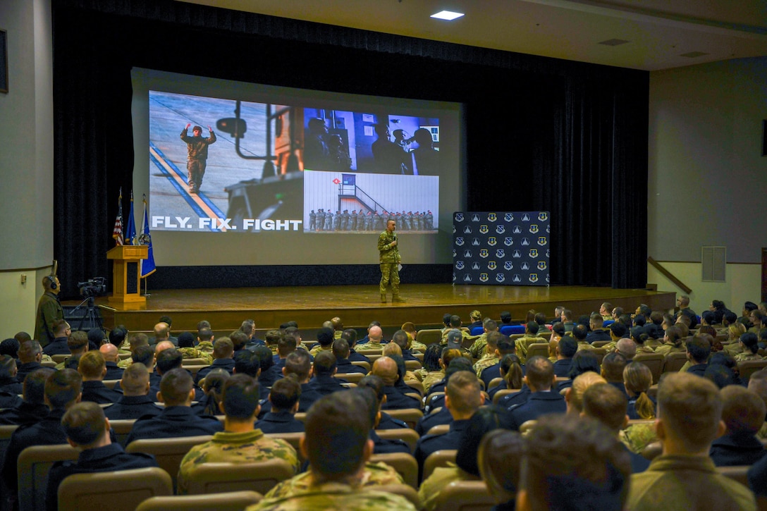 Airman speaks to crowd of troops.