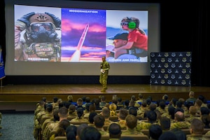 Airman speaks to crowd of troops.