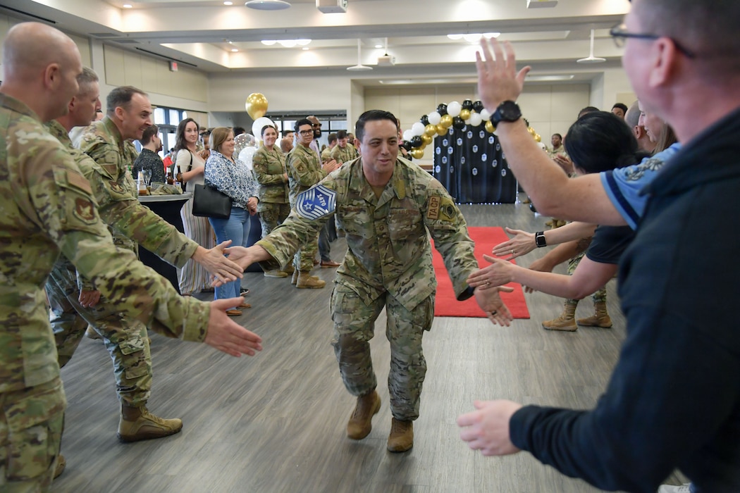 A man in military uniform works his way down a line of people while giving high-fives.