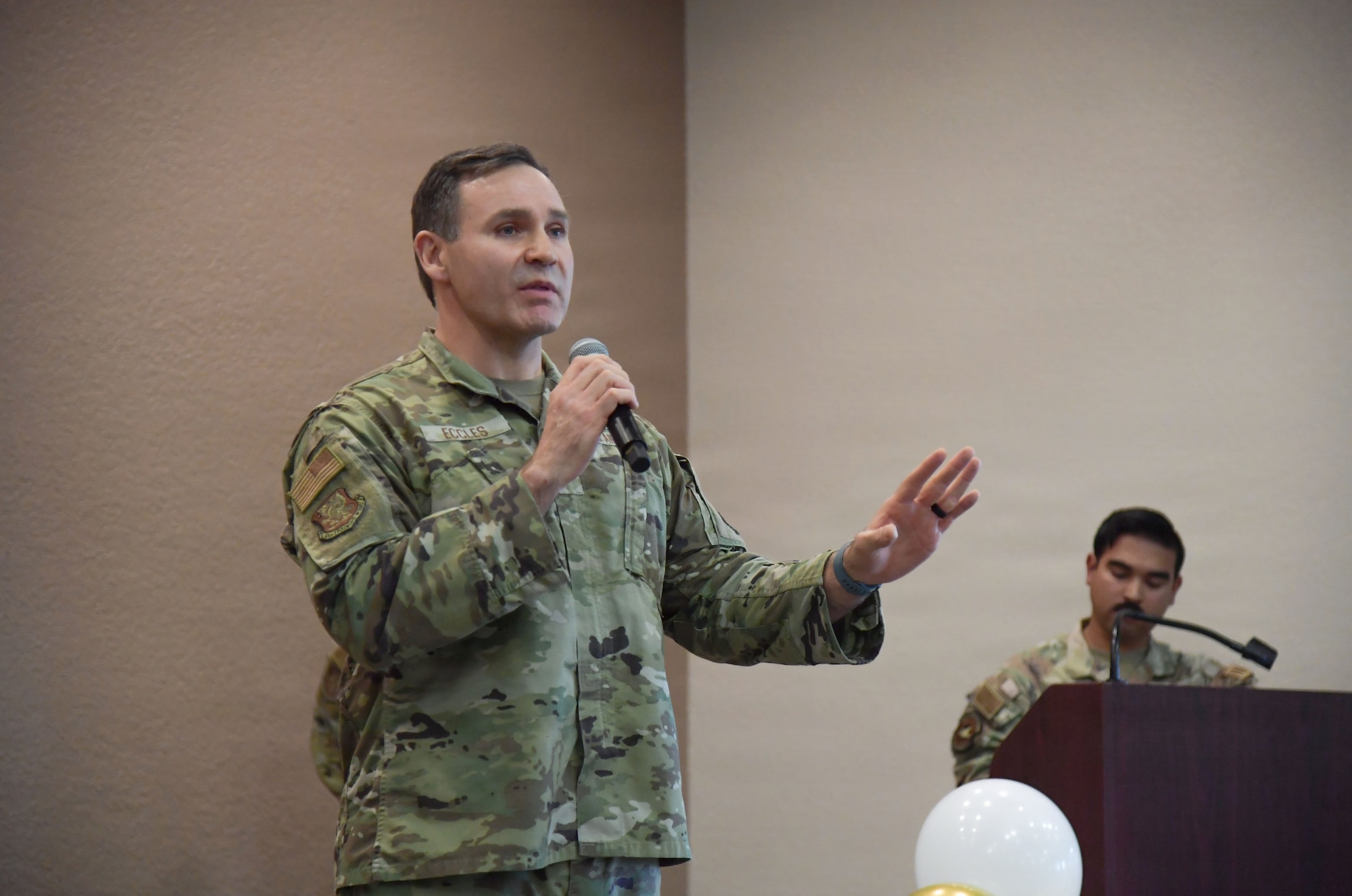 A man wearing a U.S. Air Force uniform speaks into a microphone.