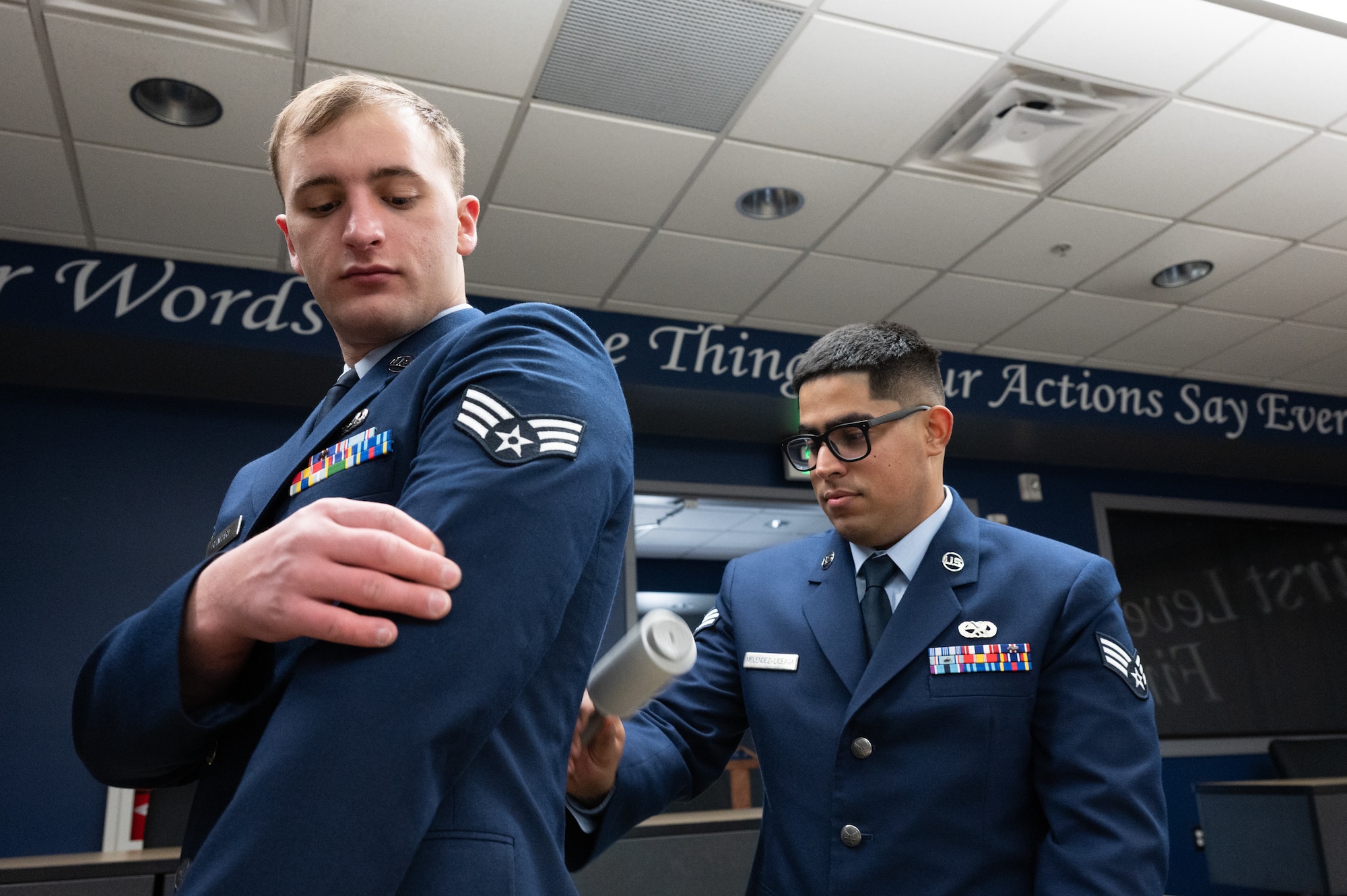 U.S. Air Force Senior Airman Timoteo Melendez Liceaga, right, 436th Aircraft Maintenance Squadron C-5M crewchief, helps Senior Airman Chase Reinhart, 436th Operations Support Squadron radar airfield weather systems trainer, prepare for a uniform inspection during the first day of Airmen Leadership School at Dover Air Force Base, Delaware, March 2, 2026. This is the first of several uniform inspections throughout the five week course. (U.S. Air Force photo by Mauricio Campino)