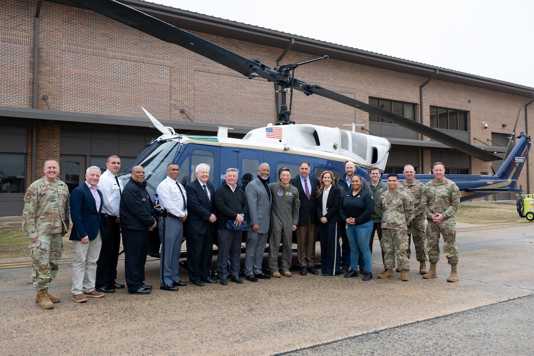 People stand in front of a helicopter.