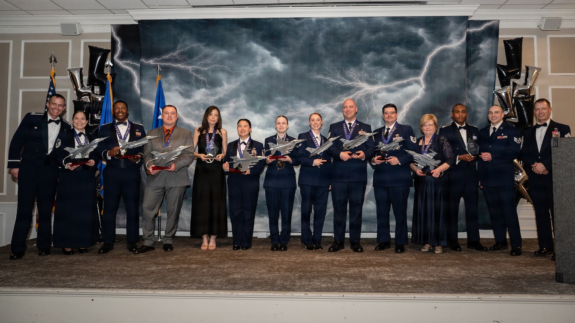 Airman and civilians pose as a group while holding trophies.