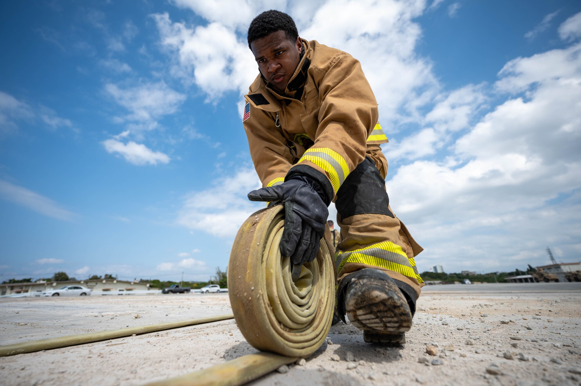 U.S. Air Force Airman 1st Class Nasir Medina, 18th Civil Engineer Squadron firefighter, rolls up a hose during U.S. Air Force-led operational exercise Beverly Midnight 26 at Kadena Air Base, Japan, Mar. 10, 2026. The synchronization of our forces enables the U.S. to serve as a premier partner to Japan. (U.S. Air Force photo by Airman 1st Class Francisco Huerta)