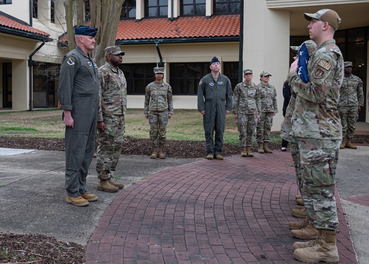 Military members stand in retreat formation as a encased flag is presented to the lead of the detail
