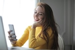 Woman in yellow shirt smiles while talking to someone on a phone