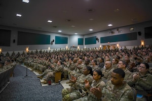 Airman speaks to crowd of troops.