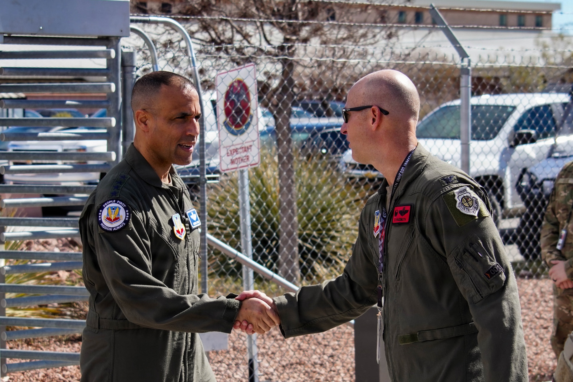 Two men in flight suits shake hands.