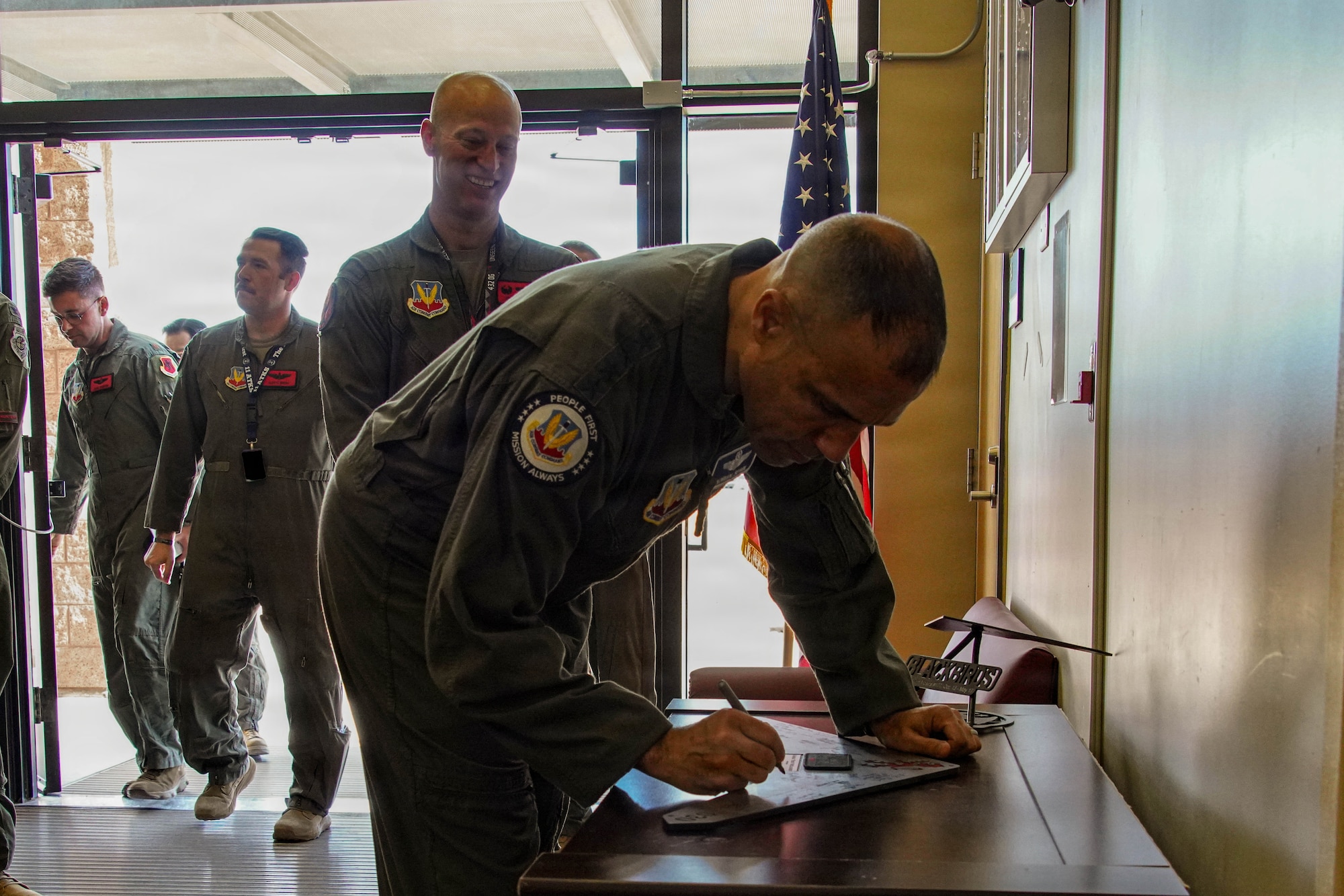 A man in a flight suit signs a plaque.