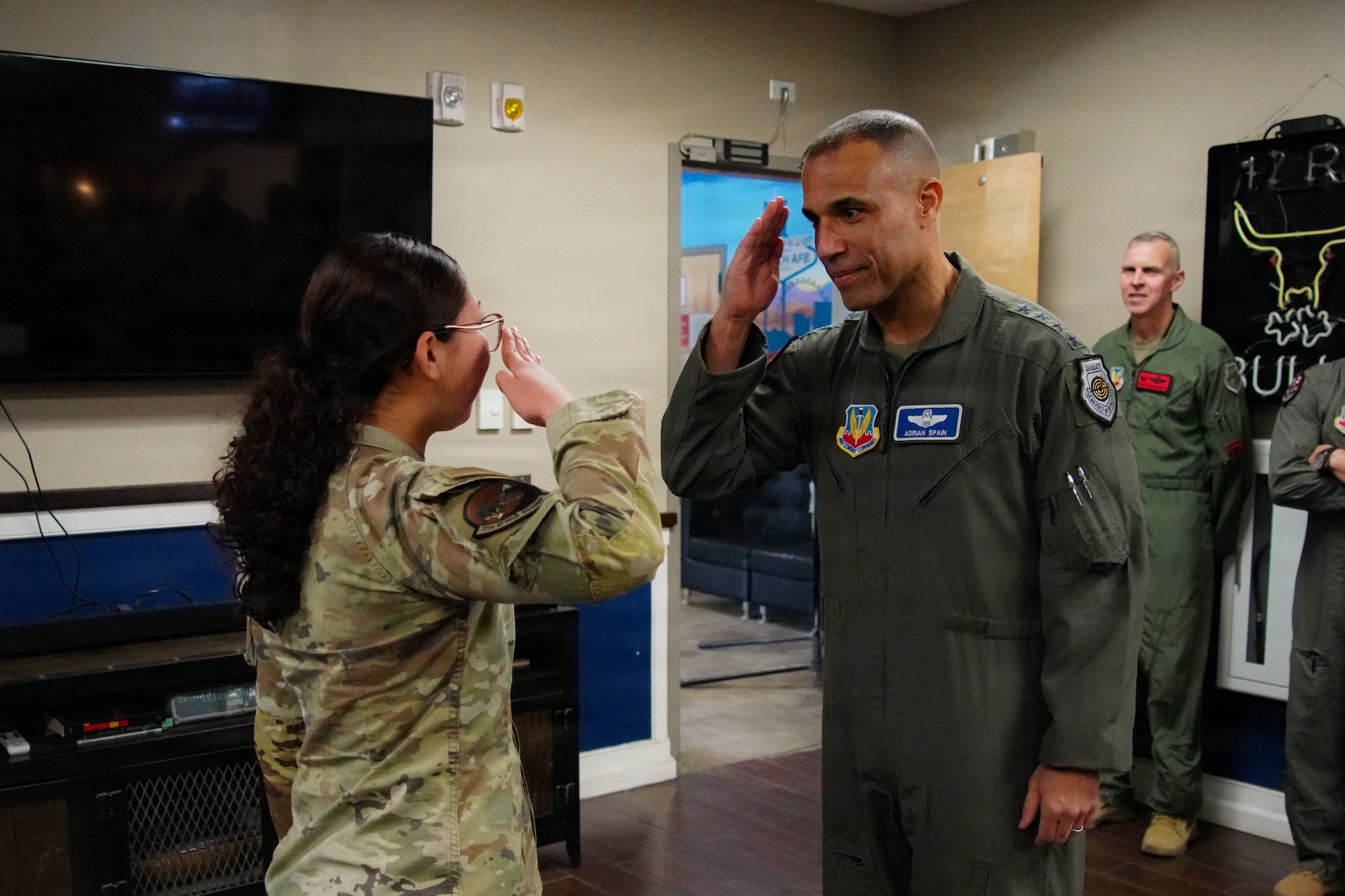 A woman in a military uniform salutes a man in a flight suit.