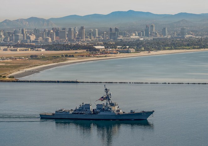 The Arleigh Burke-class guided-missile destroyer USS Mustin (DDG 89) transits San Diego Bay past Point Loma, Feb. 23, 2026. The ship departed Naval Base San Diego and will forward deploy to Yokosuka, Japan, as part of a scheduled rotation of forces in the Pacific. (U.S. Navy photo by Mark D. Faram)