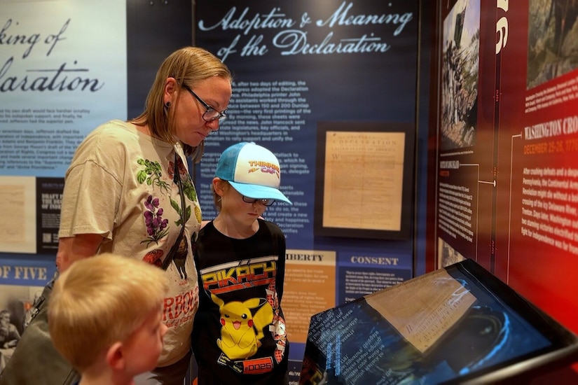 A woman and two children observe a historical display in a mobile museum.