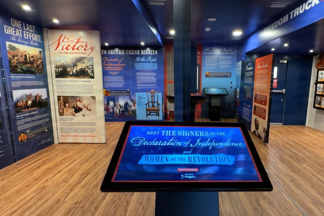 A tablet is displayed in a room with historical artwork on the walls.