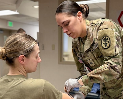 After completing a blood draw, Sgt. Felicia Wells, a medical laboratory specialist at Munson Army Health Center, Fort Leavenworth, Kansas, places a dressing around the arm of Capt. Blake Cremin, company commander, Headquarters and Headquarters Company 329th Combat Sustainment Support Battalion, out of Parsons, Kansas, Feb. 19. Soldiers from the 329th traveled to Munson to complete annual medical readiness processing to ensure the unit remains medically ready to answer the nation’s call