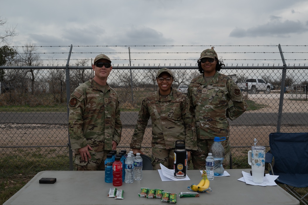 Volunteers at station 2 pose for a group photo during the inaugural Noncommissioned Officer Ruck March at Goodfellow Air Force Base, Texas, March 5, 2026. Volunteers at station 2 added weight to one participant’s ruck to symbolize bearing the weight of being a NCO and how to seek guidance for it. (U.S. Air Force photo by Senior Airman Brian Lummus)