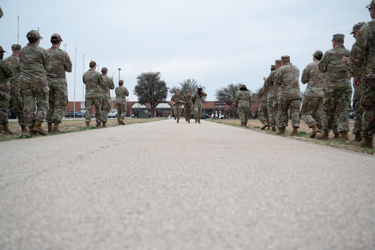 Participants run towards the finish line during the inaugural Noncommissioned Officer Ruck March at Goodfellow Air Force Base, Texas, March 5, 2026. Senior enlisted personnel waited at the end of the ruck to congratulate the new NCOs for finishing the ruck. (U.S. Air Force photo by Senior Airman Brian Lummus)