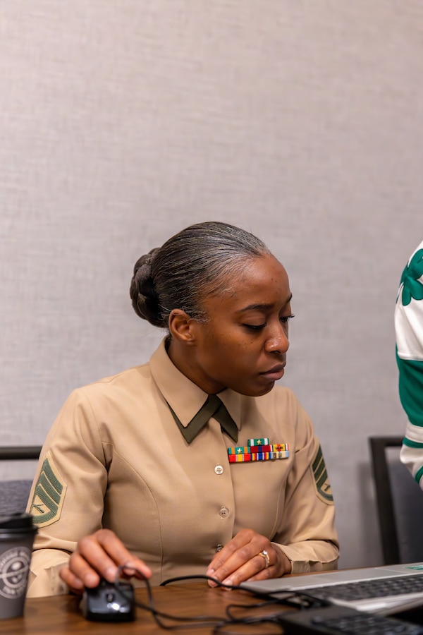 U.S. Marine Corps Staff Sgt. Abeo F. Johnson, an administrative clerk with Force Headquarters Group, Marine Forces Reserve, assists an Individual Ready Reserve Marine with administrative documents during the Individual Ready Reserve muster at Arlington, Virginia, March 7, 2026. Marine Corps Individual Reserve Support Activity conducts administrative screenings of IRR Marines to ensure readiness to augment and reinforce the active component. (U.S. Marine Corps photo by Sgt. Emely Gonzalez)