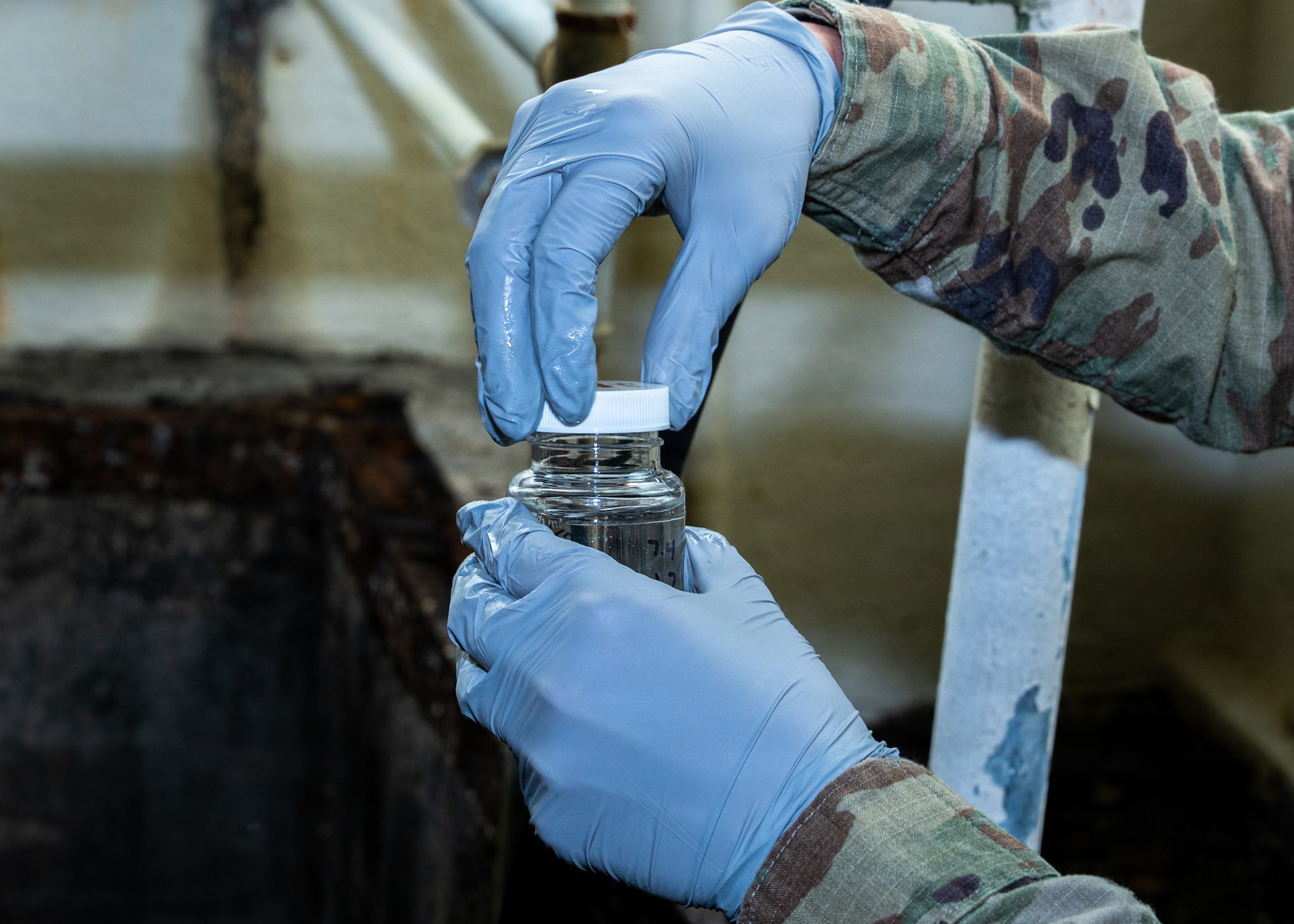 Two hands close the lid on a small jar of water