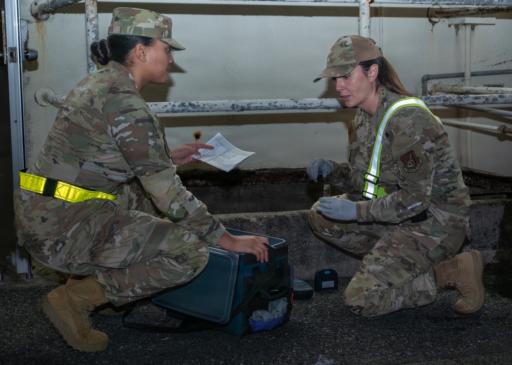 Two women crouched by a well