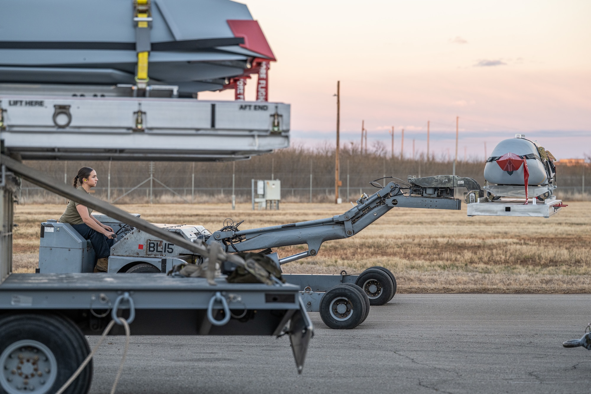 U.S. Air Force Airman 1st Class Maya Roberto, 7th Munitions Squadron armament maintenance member, moves a Launcher Load Frame with a Joint Air-to-Surface Standoff Missile to be loaded onto a B-1B Lancer at Dyess Air Force Base, Texas, Feb. 14, 2026. Integrated across platforms such as the B-1B Lancer, B-52H Stratofortress and F-15E Strike Eagle, JASSM employment relies on coordination between multiple units to synchronize build-up, delivery and load operations under tight timelines. (U.S. Air Force photo by Airman 1st Class Caleb Schellenberg)