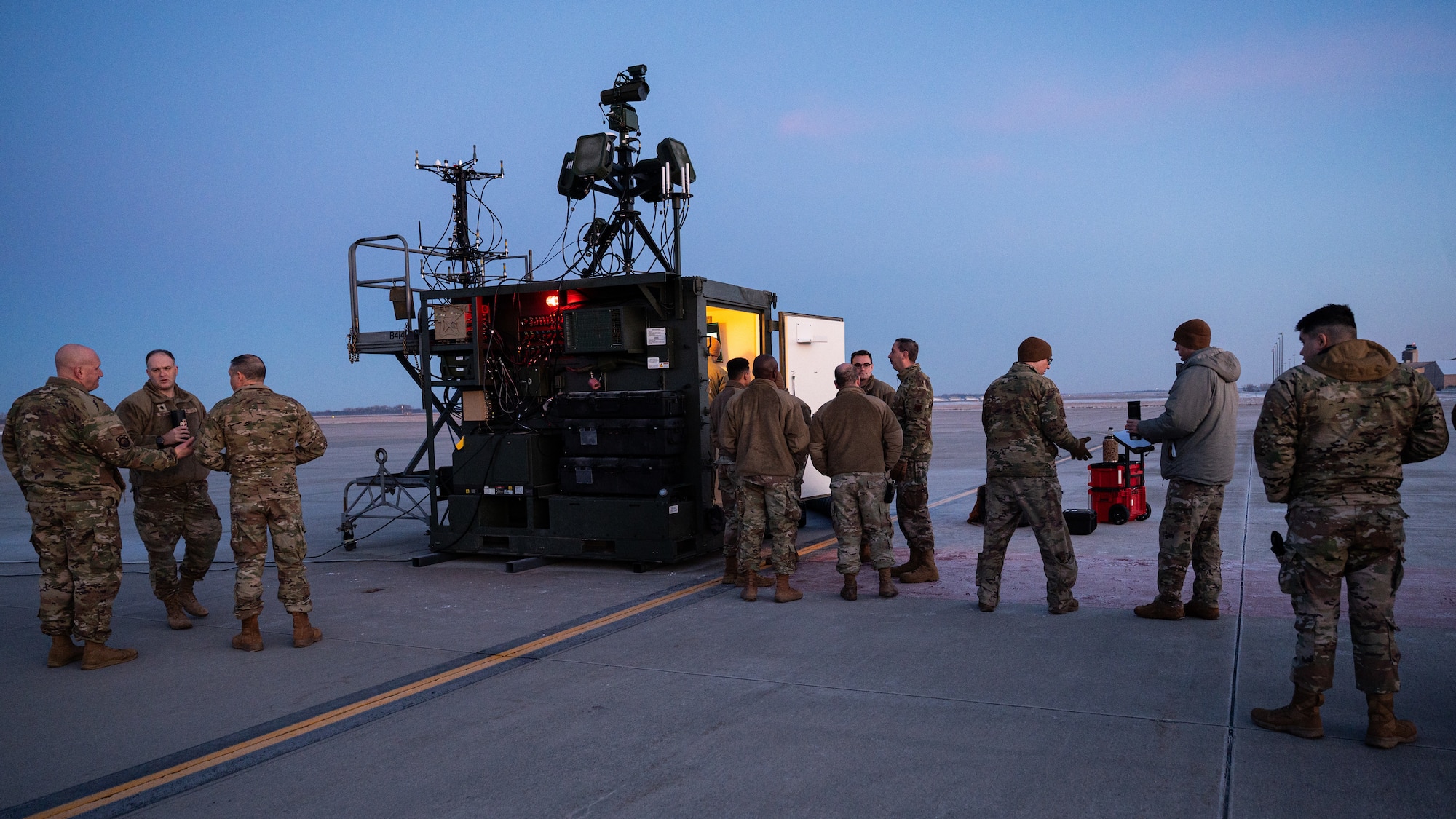 A photo of a group of people standing and walking outside on a flightline.