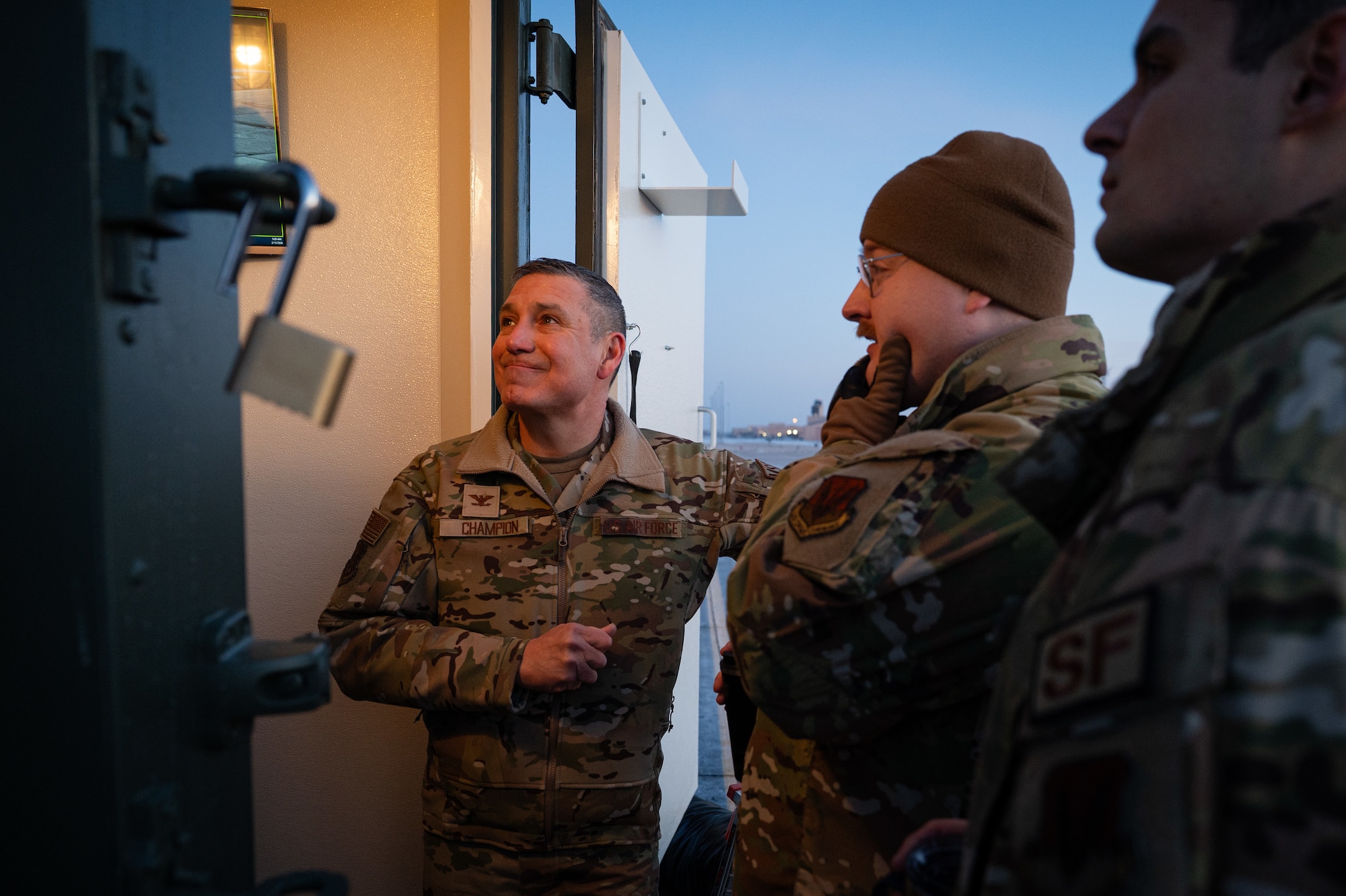 A photo of three men standing outside on a flightline.
