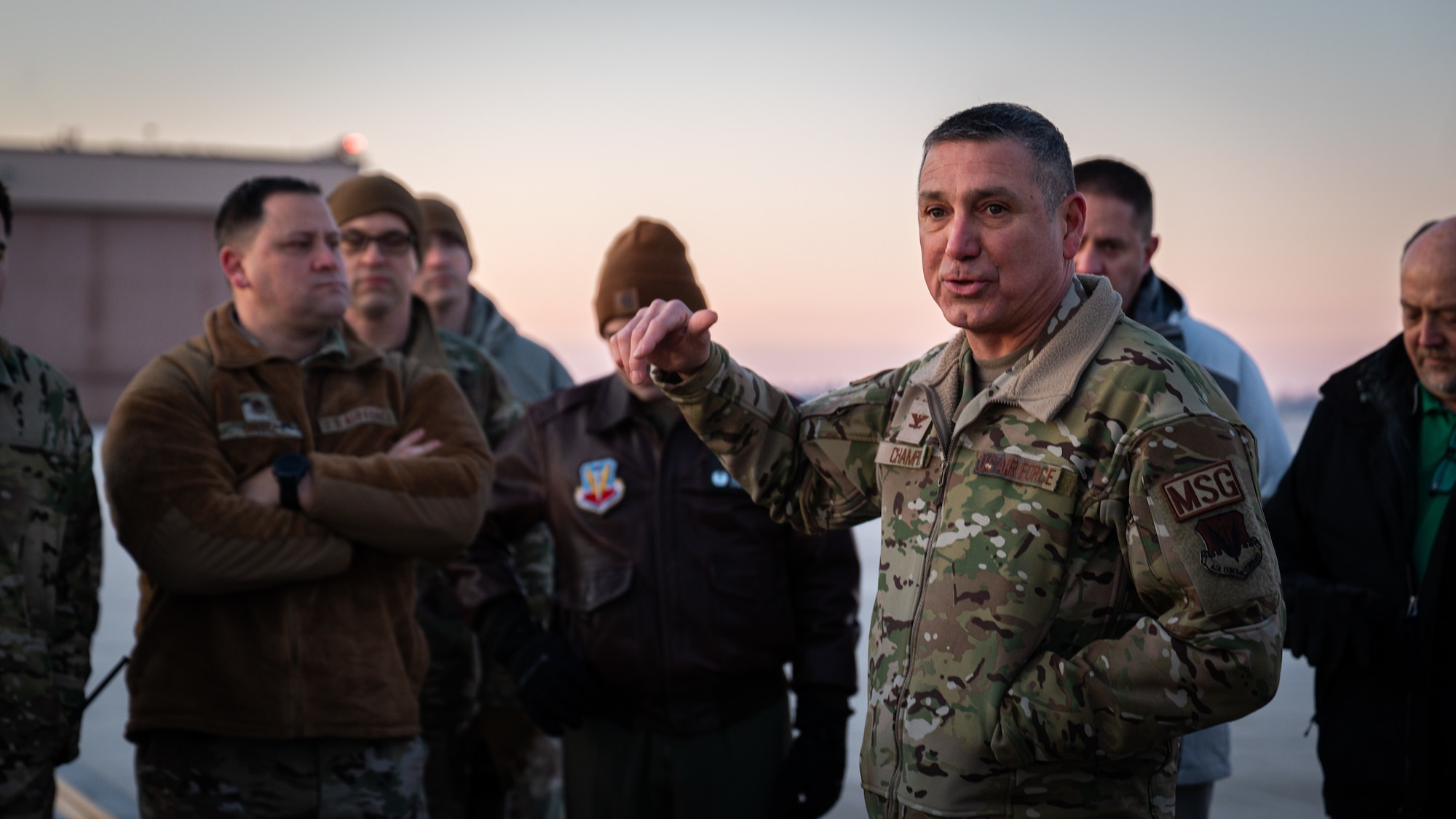 A photo of a man speaking to a group of people outside.